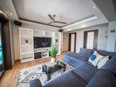 a living room with a blue couch and a tv at 4br Penthouse With Rooftop Pool In Sosua Strip in Sosúa