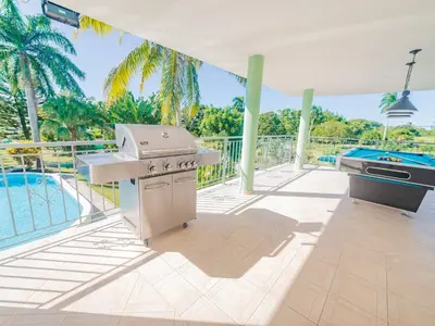 an outdoor kitchen with a grill and a swimming pool at 7br Massive Villa In Sosa - 2mins From Nightlife in Sosúa