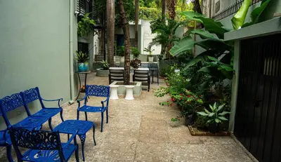 a patio with blue chairs and tables and plants at Hotelito Bonito Eli & Edw in Santo Domingo