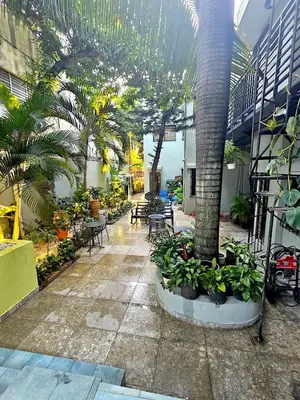 a courtyard with tables and palm trees in a building at Hotelito Bonito Eli & Edw in Santo Domingo