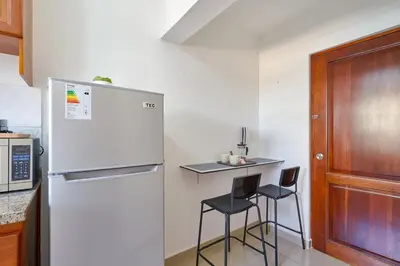 a kitchen with a refrigerator and two bar stools at Escape Studio Close to Agora Mall in Santo Domingo