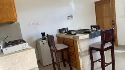 a kitchen with two chairs and a counter with a refrigerator at Apartamentos JGB in Sosúa Abajo
