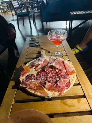 a pizza on a wooden table with a drink at Hotel Vista Caribe Azúa in Azua de Compostela