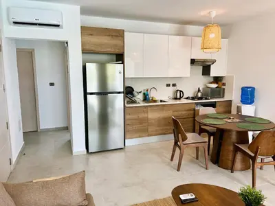 a kitchen with a table and a stainless steel refrigerator at Beautiful Star of the Caribbean - Apartment Estrella Dominicus Bayahibe in La Laguna