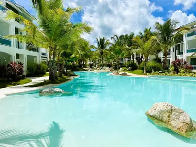 a swimming pool with blue water and palm trees at Beautiful Star of the Caribbean - Apartment Estrella Dominicus Bayahibe in La Laguna