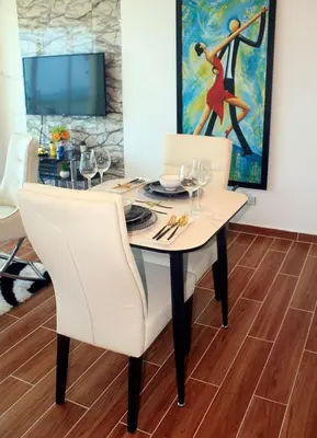 a dining room table with white chairs and a painting at Sturning Ocean View. in Santo Domingo