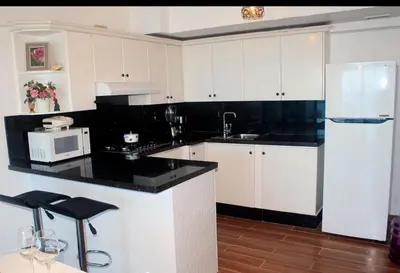 a kitchen with white cabinets and a black counter top at Sturning Ocean View. in Santo Domingo
