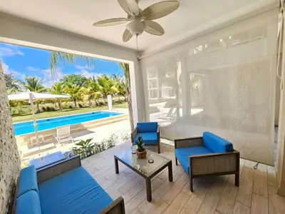 a living room with blue furniture and a view of a pool at Comfort Condo w/Pool View at Hard Rock Golf Course in Punta Cana