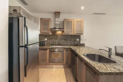 a kitchen with wooden cabinets and a stainless steel refrigerator at Wonderful 1-BR apartment at Casa de Campo in El Infiernito