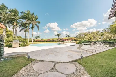 a swimming pool with benches and palm trees at Wonderful 1-BR apartment at Casa de Campo in El Infiernito