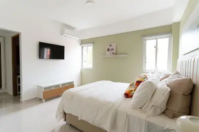 a white bedroom with a bed and a television at LANDA MAR BOCA CHICA in Boca Chica