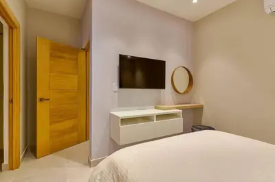 a bedroom with a bed and a mirror and a television at Oasis Urbano Family 2br Pool Gym Lm22-8B in Santo Domingo