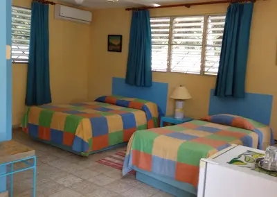 a bedroom with two beds and blue curtains at Casa Sylvie in Sosúa