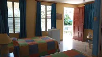 a bedroom with a bed and a door with blue curtains at Casa Sylvie in Sosúa