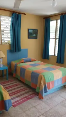 a bedroom with two beds and blue curtains at Casa Sylvie in Sosúa