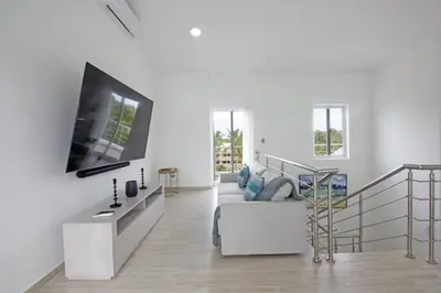 a white living room with a tv on a wall at Amplio PH de 3 hab para 9 personas in Punta Cana