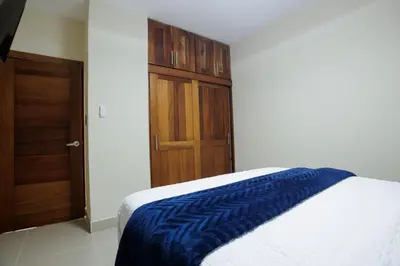 a bedroom with a bed with a blue blanket on it at Luxury Penthouse in San Francisco de Macorís