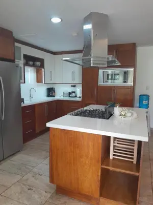 a kitchen with wooden cabinets and a white counter top at Balcones Del Atlantic Beachfrontbbq in Las Terrenas