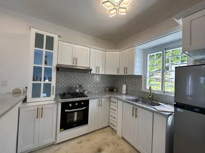 a kitchen with white cabinets and a sink and a stove at Casita Yanella in Cabrera