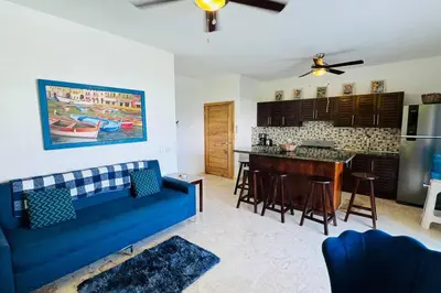 a living room with a blue couch and a kitchen at La Fenice Beachfront with King Beds in Las Terrenas