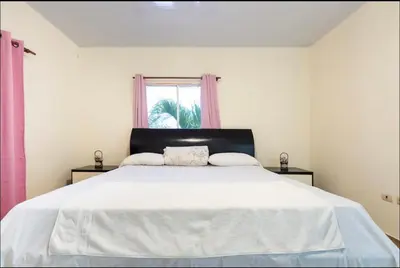 a bedroom with a large white bed with a window at Casa Mami in Río San Juan