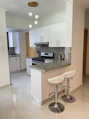 a kitchen with white cabinets and a counter with stools at Torre Sophia Monserrat in Los Frailes