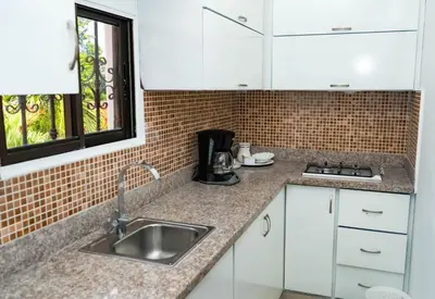 a kitchen with white cabinets and a sink at Guacamayos Hotel in Bonao