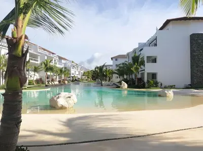 a resort swimming pool with a palm tree and buildings at Acogedor apartamento en Estrella Dominicus in La Laguna