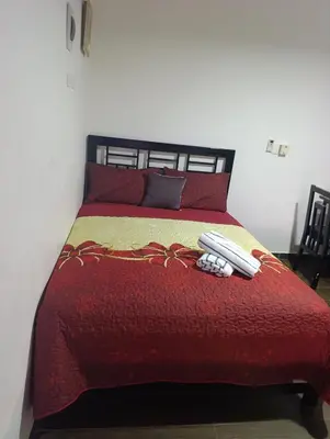 a bed with a red comforter and two pillows at Apart hotel Costa Verde #3 Exclusivo y Seguro in Santa Bárbara de Samaná