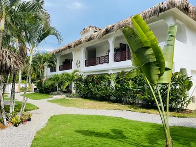 a house with a palm tree in front of it at Empyrean Tropical Wellness Portillo in Las Terrenas