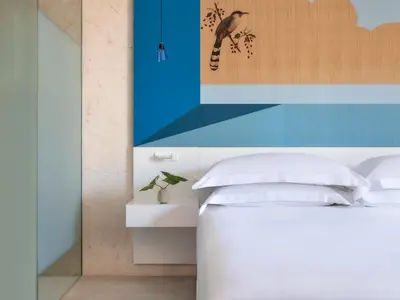 a bedroom with a white bed and a painting on the wall at Kimpton Las Mercedes by IHG in Santo Domingo