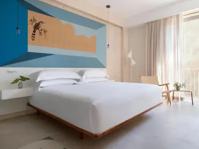 a white bed in a room with a blue wall at Kimpton Las Mercedes by IHG in Santo Domingo