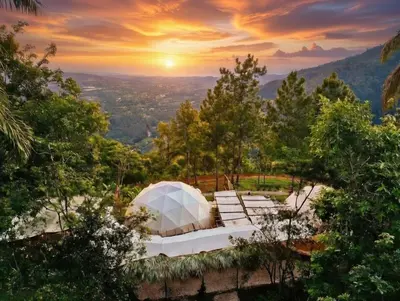 a tent on a hill with a sunset in the background at NOMAD Domes Sky Watching at Jarabacoa in Jarabacoa