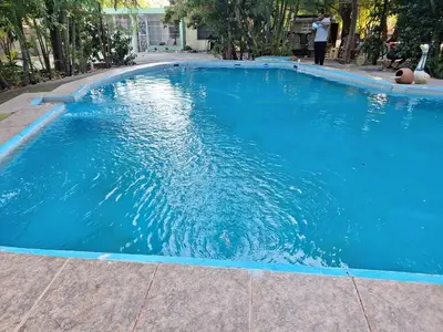 a large blue swimming pool with a person standing in it at Hotel Villa Marchena in Azua de Compostela