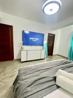 a bedroom with a large bed and a large tv at Super Cozy n´Confortable apart. in Ensanche Los Minas