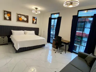 a bedroom with a bed and a desk and windows at RIG Colonial Experience in Santo Domingo