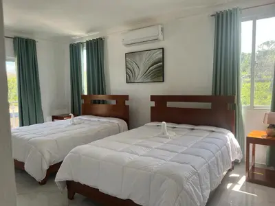 two beds in a bedroom with green curtains at Luxury Beach Front Villa with Private pool and stunning Ocean View! in Punta Rucia