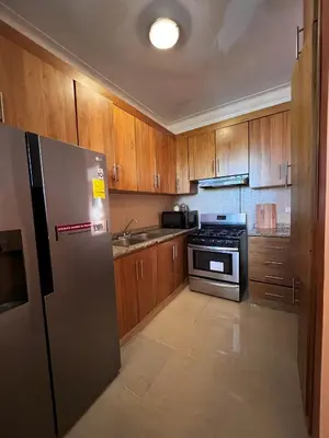 a kitchen with wooden cabinets and a stainless steel refrigerator at Bello Apartamento en Santiago con todas las comodidades in Santiago de los Caballeros