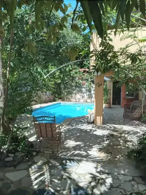 a swimming pool with two chairs in front of a house at Villa rozenuda in Boca Chica