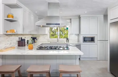 a kitchen with white cabinets and a stove top oven at Kite Beach Penthouse in Cabarete