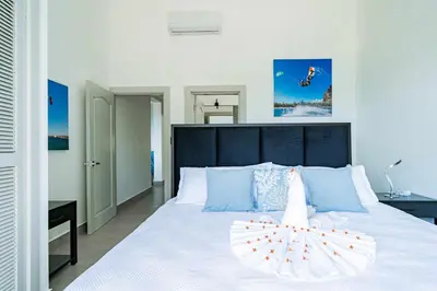 a bedroom with a large white bed with blue pillows at Kite Beach Penthouse in Cabarete