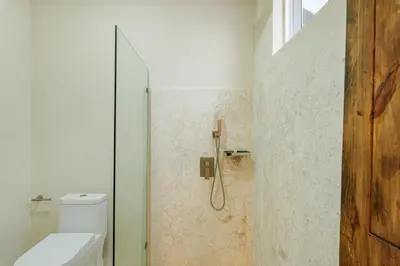 a bathroom with a toilet and a glass shower at Enriquillo 2-Bedroom Apt Casa Areito in Santo Domingo