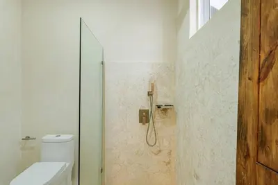 a bathroom with a toilet and a glass shower at Guacanagarix 2-Bedroom Apt Casaareito in Santo Domingo