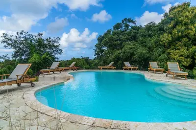 a swimming pool with benches around it with trees at Margarita Ecovillage in Miches