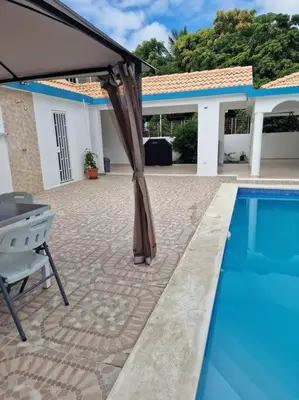a patio with an umbrella and a swimming pool at Lujosa y espaciosa Villa María. in Santiago de los Caballeros