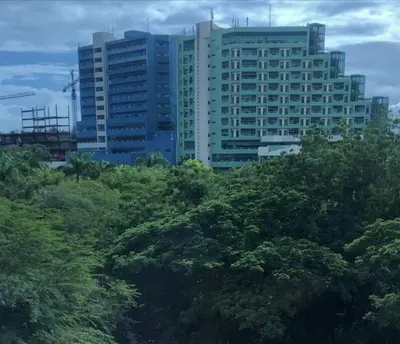 a tall building with trees in front of it at Acogedor Sweet Apartament in Santiago de los Caballeros