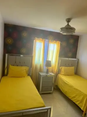 two beds in a room with yellow sheets at Acogedor Sweet Apartament in Santiago de los Caballeros