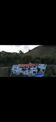 a large white house in the middle of a hill at Mango y Jobo - Relaxed Mountain & Sea Panoramic view - 10mins drive to beach and city in San Felipe de Puerto Plata