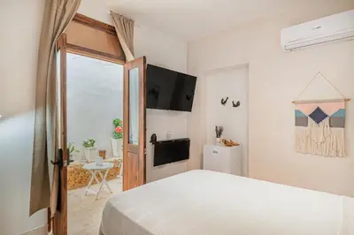 a white bedroom with a bed and a television at 3 Studios at Casa Areito in Santo Domingo