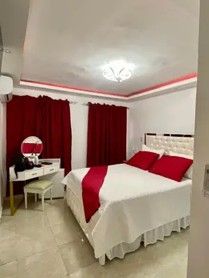 a bedroom with a large bed and red curtains at Nice and Breezy Apartment in Santiago de los Caballeros